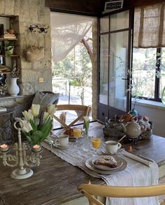 a wooden table topped with lots of breakfast food next to a glass door leading to an outside patio