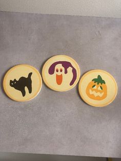 three coasters with halloween designs on them sitting on a counter top in front of a wall