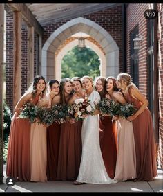 a group of women standing next to each other in front of a brick wall and archway