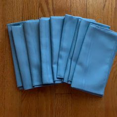 six folded blue napkins sitting on top of a wooden table