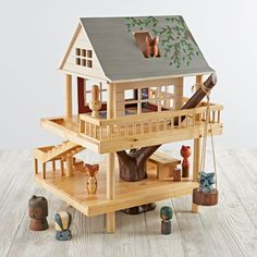 there is a doll house on top of a table with other toys around the tree