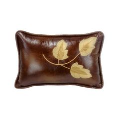 a brown leather pillow with yellow leaves on it