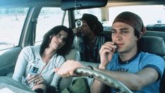 three people sitting in the back seat of a car talking on their cell phones and drinking beverages