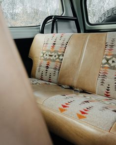 the interior of a vehicle with leather seats and decorative pillows on it's armrests