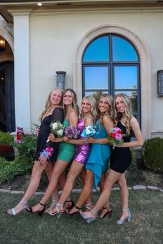 four beautiful young women standing next to each other in front of a house