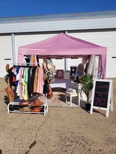 a pink tent with clothes hanging from it's sides and a sign on the ground