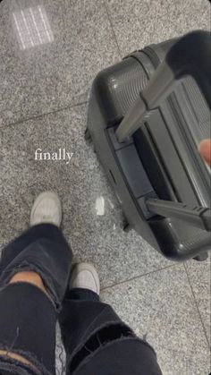 a person standing next to a piece of luggage on top of a tile floor in an airport