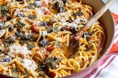 a pan filled with pasta and vegetables on top of a red and white striped towel