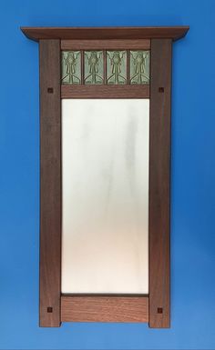 a mirror mounted to the side of a blue wall next to a wooden framed object