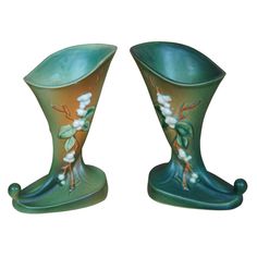 two green vases with white flowers on them are sitting next to each other in front of a white background