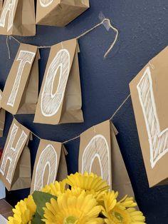 some brown paper bags are hanging on a wall with sunflowers in front of them