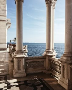 an outdoor area with columns and tiled flooring near the water's edge, looking out to sea