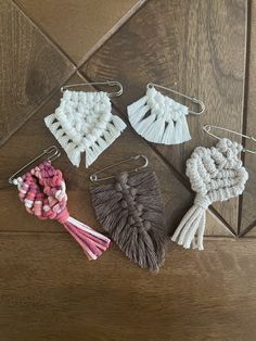 four tasselled pieces of fabric on a wooden floor with hooks and clips attached to them