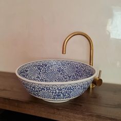 a blue and white bowl sink sitting on top of a wooden counter next to a faucet