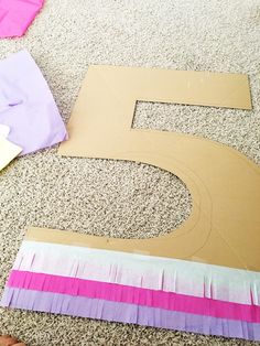 the number five is made out of cardboard and strips of colored paper on the floor