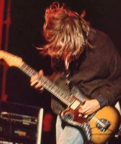 a man with long hair playing an electric guitar