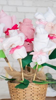 a basket filled with pink and white baby ones on top of a wooden table next to a brick wall