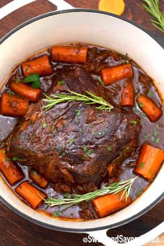 pot roast with carrots and gravy in a white bowl on a wooden table