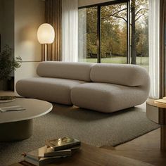 a living room filled with furniture and a large window overlooking the trees in the distance