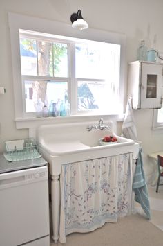 a white sink sitting under a window next to a dishwasher and dryer