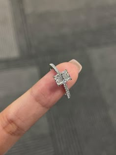 a person's finger with a diamond ring on it