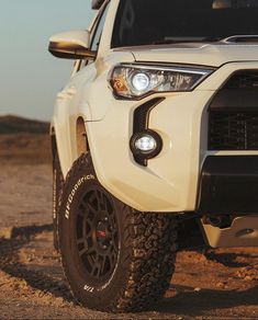 the front end of a white toyota 4runner truck on dirt road with sky in background