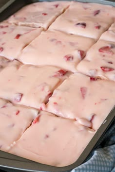 a pan filled with white chocolate covered in pink icing and cranberry toppings