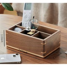 a remote control sitting in a wooden box on a table next to a cell phone