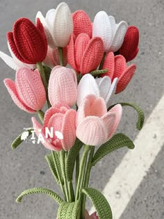 there is a crocheted vase with flowers in it on the side of the road