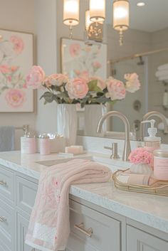 a white bathroom with pink flowers and towels on the counter top, in front of a large mirror