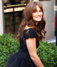 a woman in a black dress is smiling for the camera