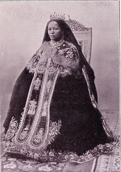 an old black and white photo of a woman wearing a costume with elaborate details on it