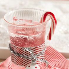 a glass filled with liquid and candy cane on top of a red striped table cloth