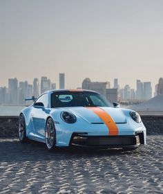 a blue and orange sports car parked in front of a city