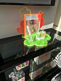 a display case with an orange and green photo frame on the glass shelf next to it