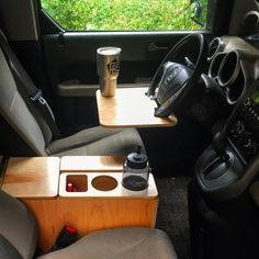 the interior of a vehicle with a cup holder and coffee mug on the table next to it