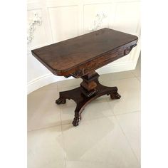 an old wooden table sitting on top of a tile floor next to a white wall