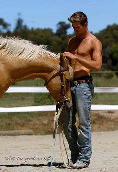 a shirtless man standing next to a brown horse