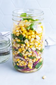 a mason jar filled with corn, onions and cilantro