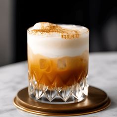 an orange and white drink sitting on top of a table next to a gold plate