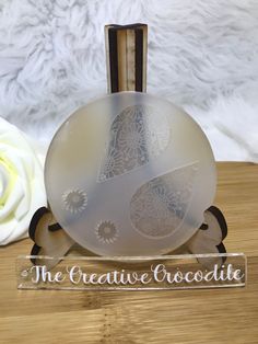 a white rose sitting on top of a wooden table next to a glass ball and plaque