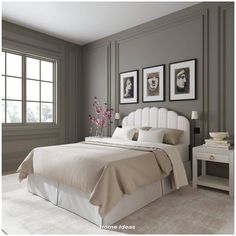 a bedroom with gray walls and white bedding, framed pictures above the headboard