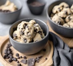 two bowls filled with cookies and chocolate chips on top of a wooden cutting board next to black napkins