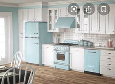 a kitchen with blue and white cabinets, wood floors and a dining table in the center