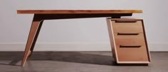 a wooden desk with three drawers on the bottom and one drawer at the top, in front of a white wall