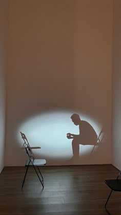 a man standing next to a chair in a room with a projected image on the wall