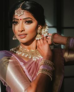 a woman in a pink sari and gold jewelry