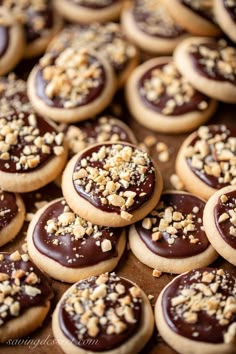 cookies with chocolate frosting and sprinkles are arranged on a baking sheet