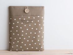 a brown and white polka dot bag sitting on top of a wooden table next to a wall