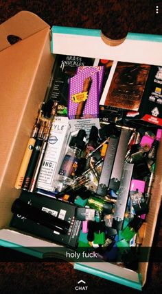 an open box filled with various items on top of a carpeted floor next to a wall